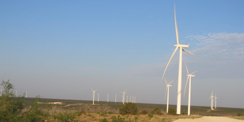 Flat landscape dotted with wind turbines.