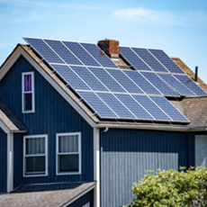 A blue two-story home with a roof covered in solar panels.
